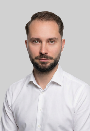 Portrait von Dominik Wittmann, Experte für Verkauf / Vermietung Gewerbe, lächelnd im weißen Hemd vor neutralem Hintergrund.