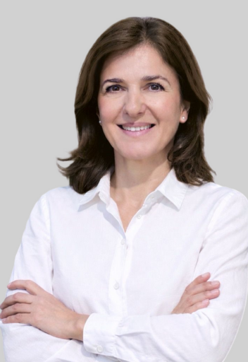 Portrait von Nicole Günsch, Assistenz bei Zenker & Günsch Immobilien, lächelnd in weißer Bluse vor neutralem Hintergrund.