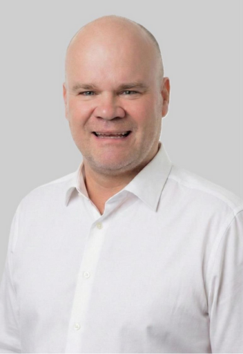 Portrait von Olaf Zenker, Inhaber von Zenker & Günsch Immobilien, lächelnd im weißen Hemd vor neutralem Hintergrund.